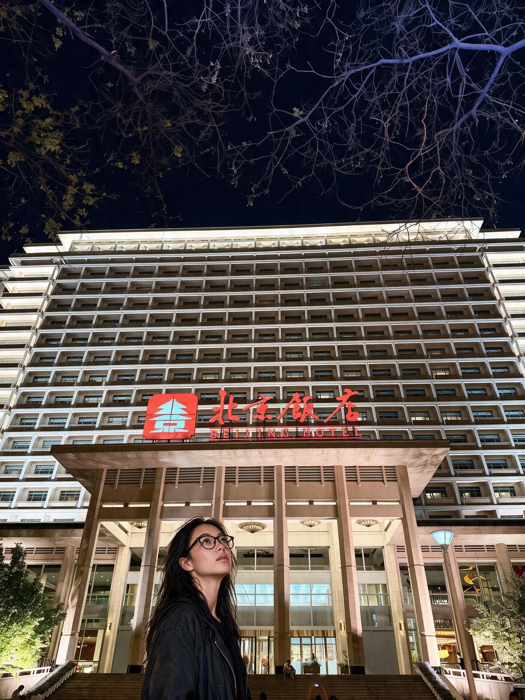 Me alone at night on the Beijing Hotel steps under the red neon.