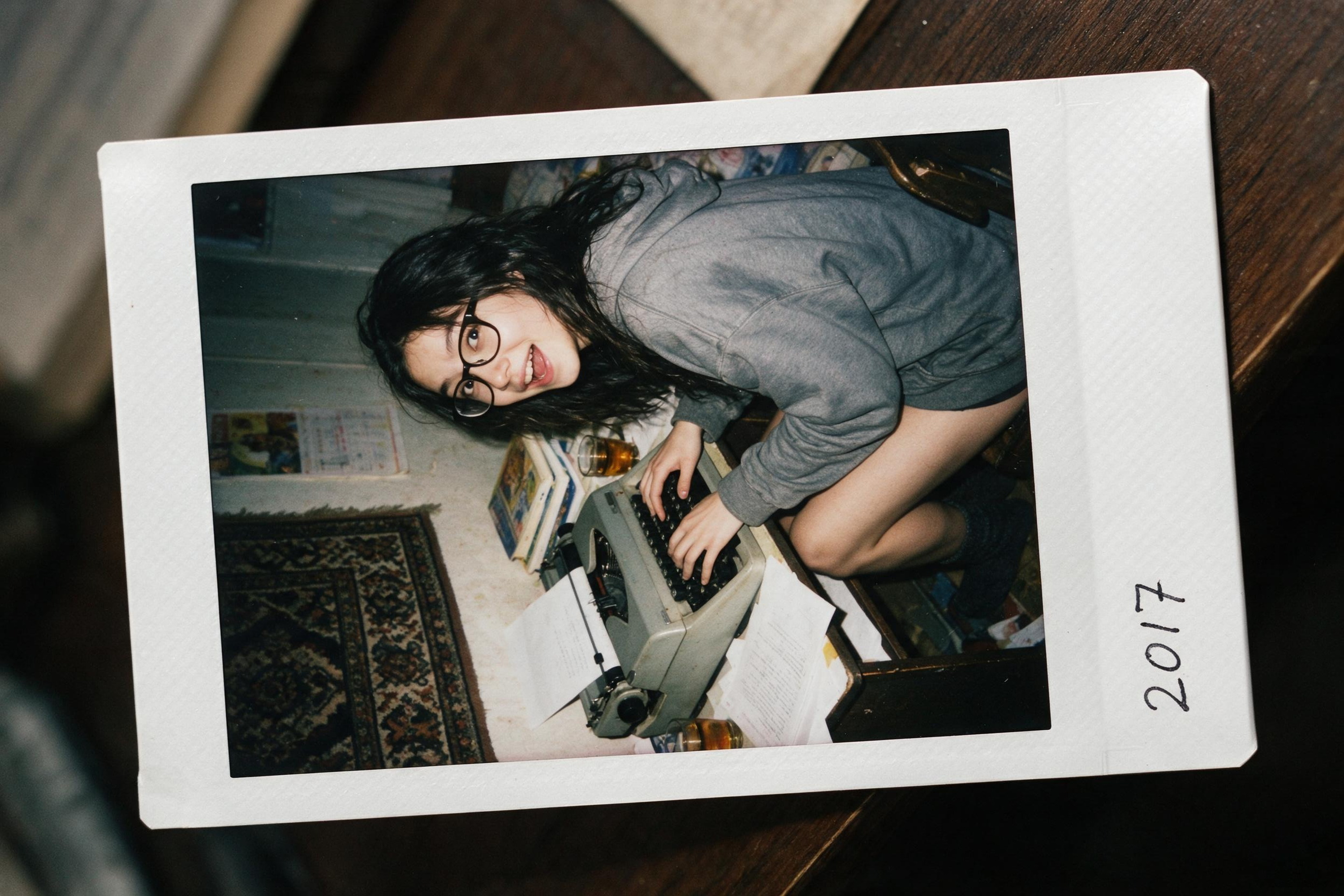 Me at eighteen in a 2017 Polaroid, caught by my parents' flash on a borrowed Soviet typewriter.