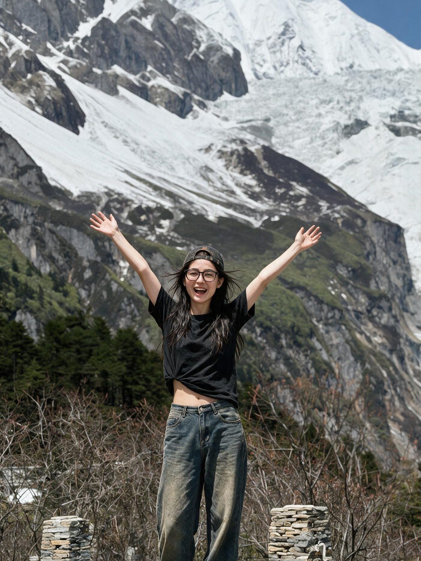Me on a boulder, both arms up, before an enormous snow-covered glacier flank.