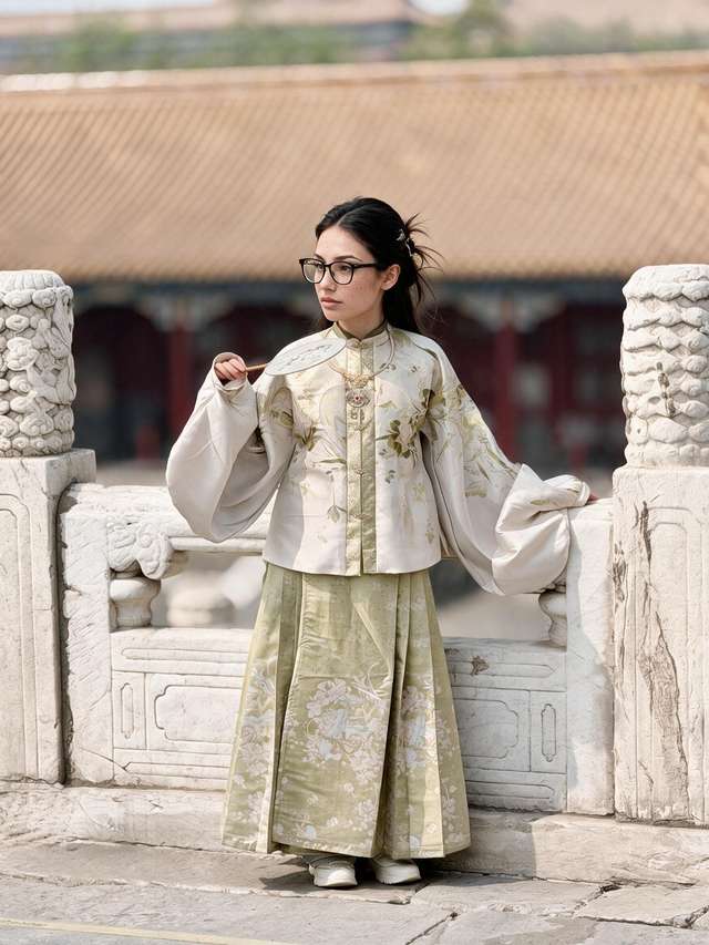Me in rented cream and green Ming hanfu, gold hair ornaments and silk fan, at a Forbidden City balustrade.