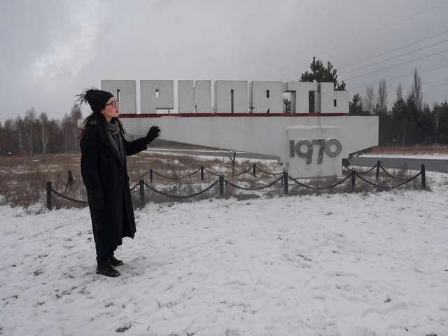 Me beside the concrete Pripyat town sign on a snowy road.