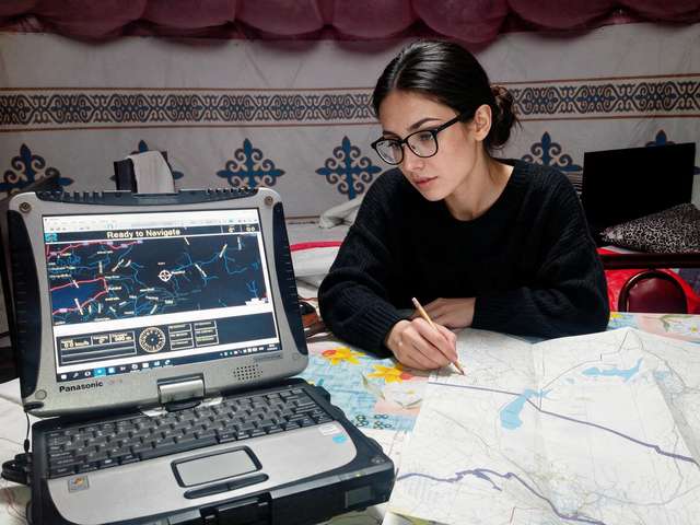 Me at a guesthouse table with paper maps and a laptop on navigation.