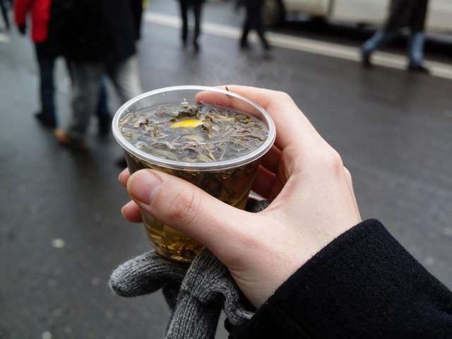 My gloved hand, a steaming plastic cup of tea, snowy Kyiv blurred behind.