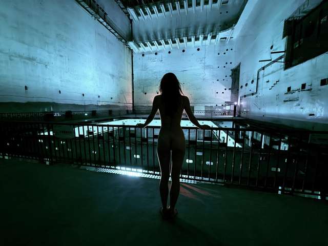 My silhouette at a gallery railing above the blue-green reactor hall of Project 816.