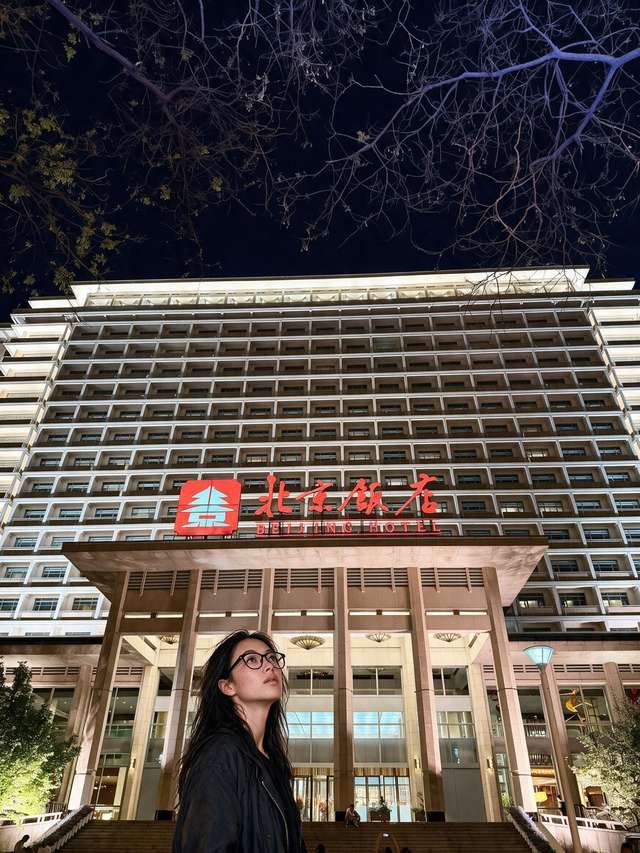 Me alone at night on the Beijing Hotel steps under the red neon.
