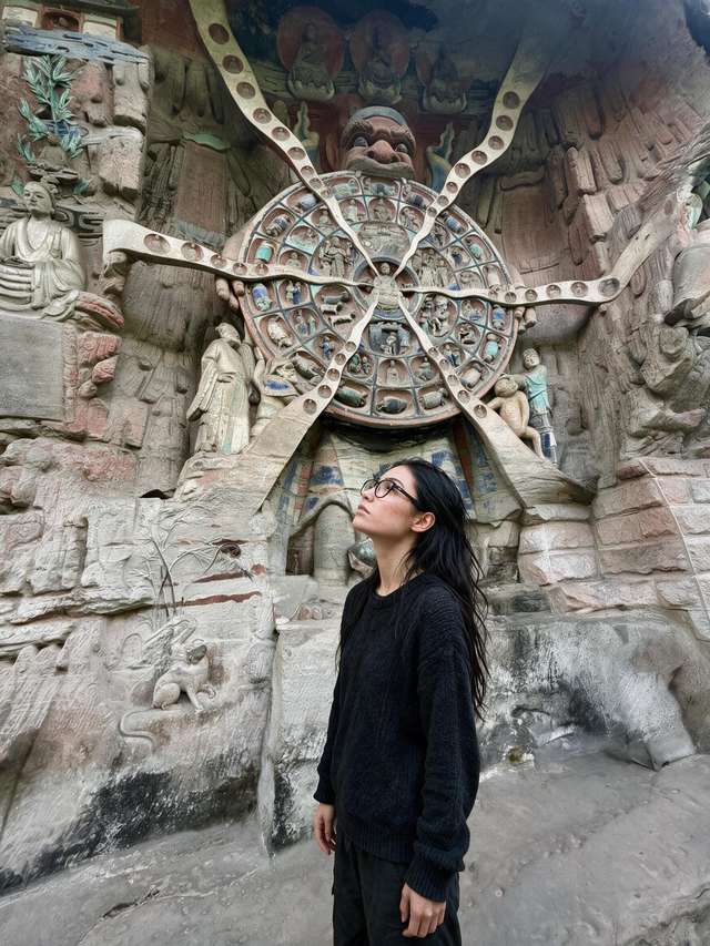Me, small before the carved Wheel of Rebirth in the Dazu rock niche.